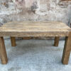 Stół Gaj - Solidna Konstrukcja Masywny dębowy stół Gaj z grubymi prostokątnymi nogami na tle ściany z cegły