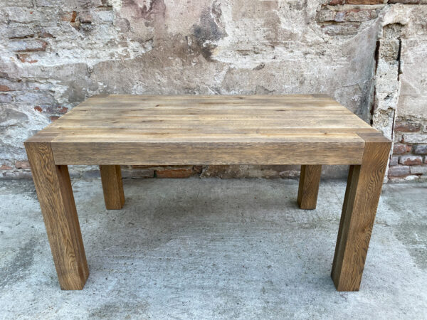Stół Gaj - Solidna Konstrukcja Masywny dębowy stół Gaj z grubymi prostokątnymi nogami na tle ściany z cegły